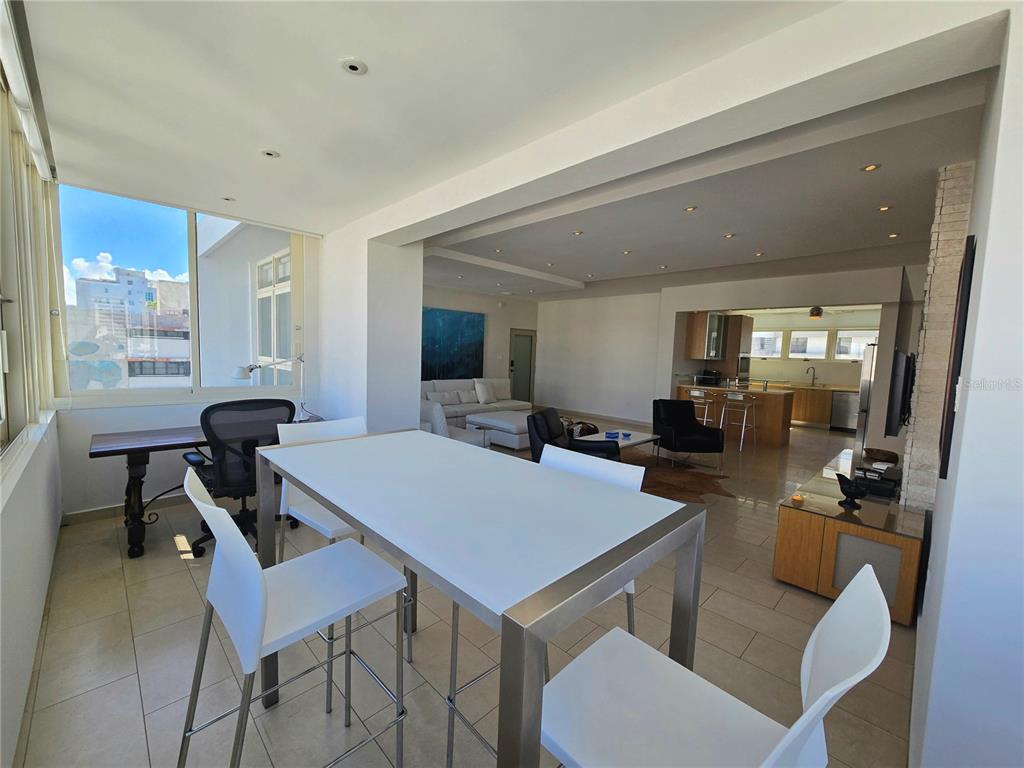 A bright, open-concept living area features a dining table, kitchen, and floor-to-ceiling windows — 1160 MAGDALENA AVENUE UNIT 7B, SAN JUAN, PR