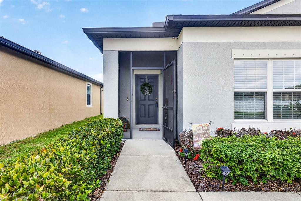 A concrete walkway leads to the front entrance of a house with a screened door — 11514 LELAND GROVES DRIVE, RIVERVIEW, FL