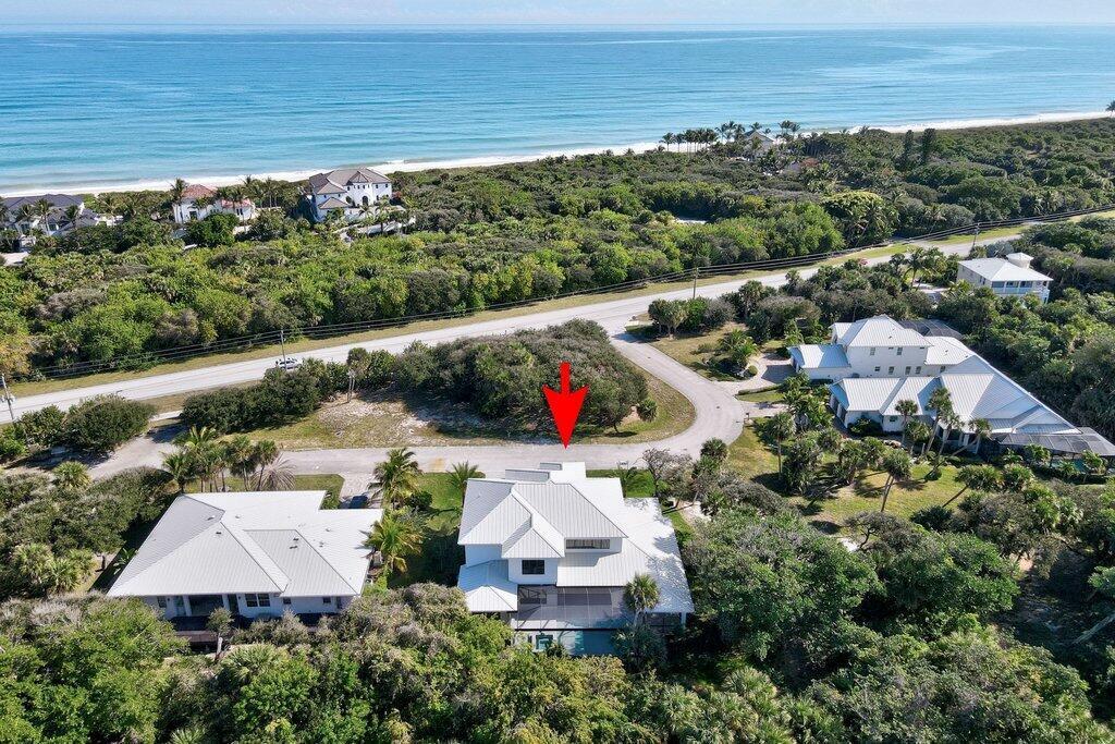 An aerial view shows a white house with a metal roof near a coastal road — 11765 Brown Pelican Way, Vero Beach FL 32963, VERO BEACH, FL