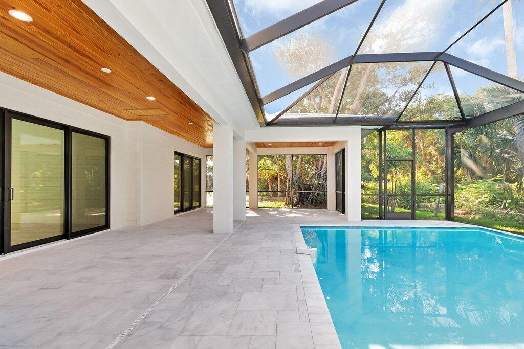 A covered patio with a wood ceiling and tile floor overlooks a screened-in swimming pool — 11765 Brown Pelican Way, Vero Beach FL 32963, VERO BEACH, FL
