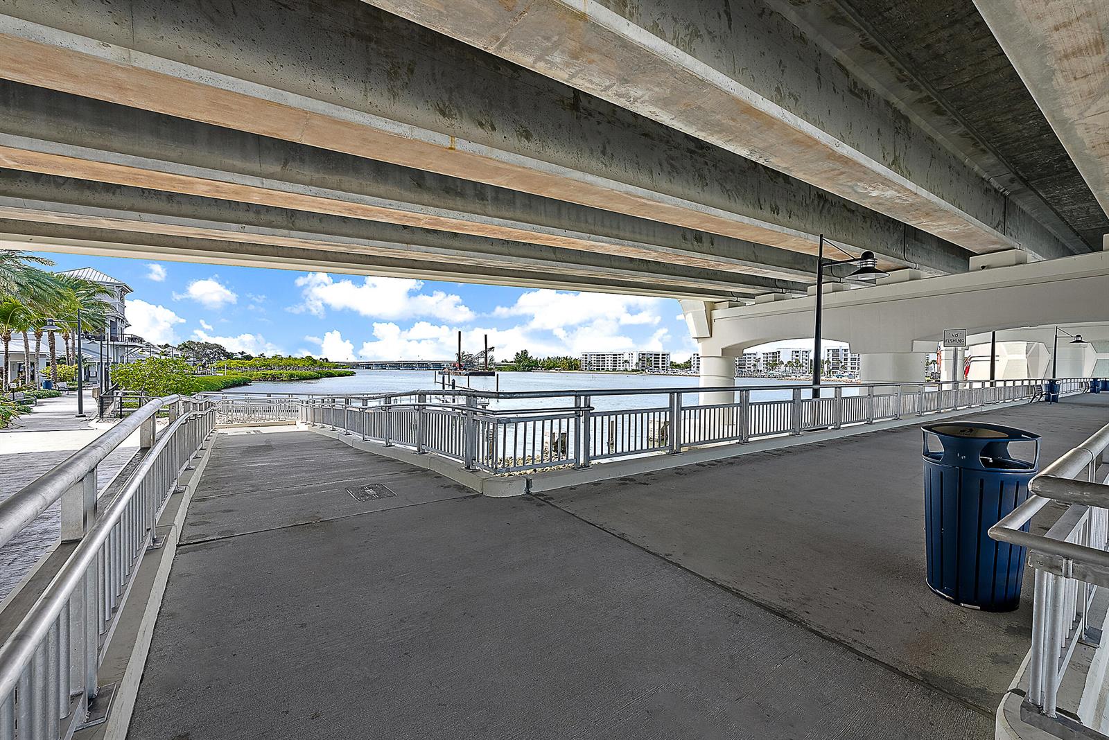 A concrete walkway under a bridge overlooks a waterway with buildings in the distance — 1000 N Us Highway 1 Highway N, Jupiter FL 33477, JUPITER, FL