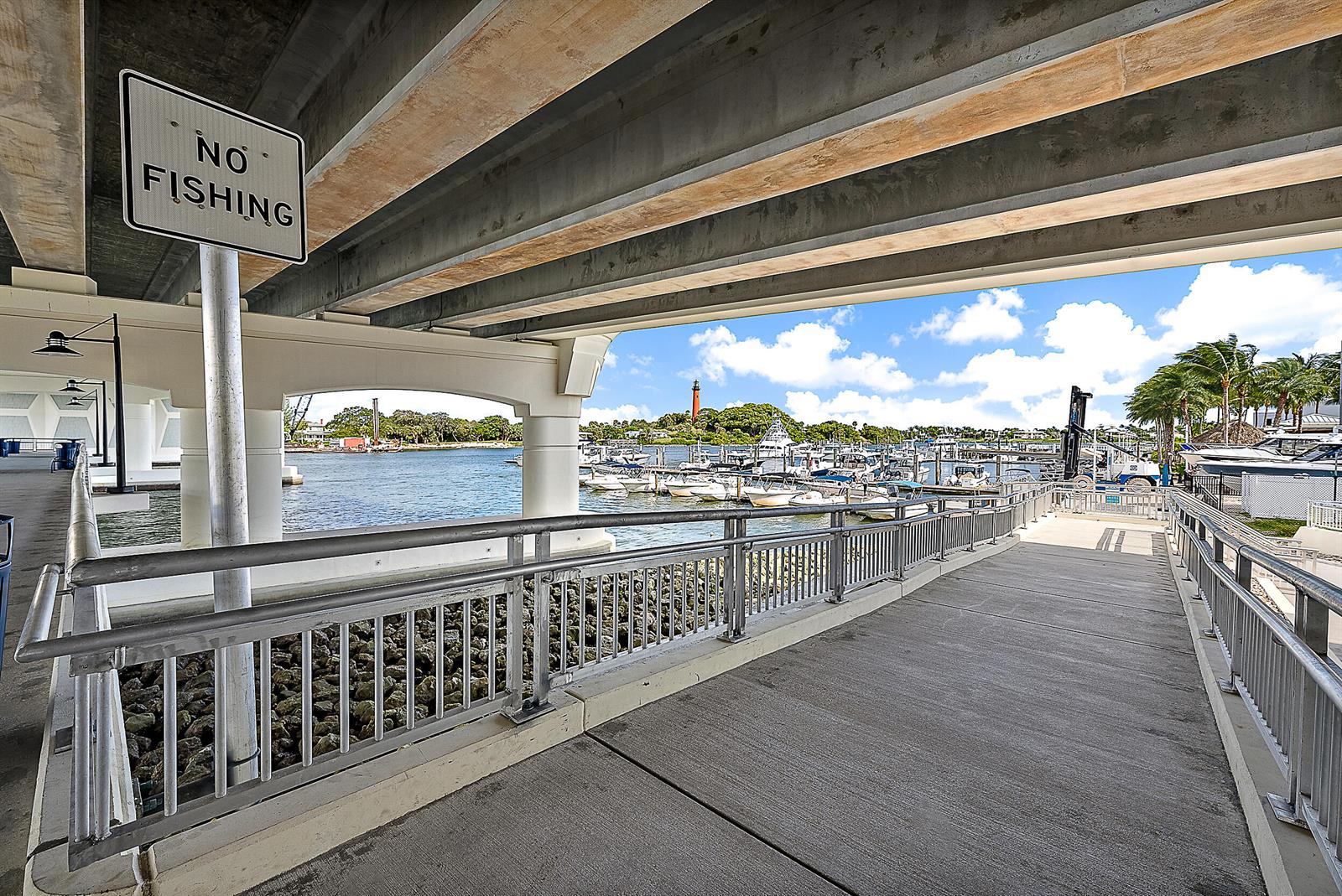 A concrete walkway under a bridge overlooks a marina with a lighthouse in the distance — 1000 N Us Highway 1 Highway N, Jupiter FL 33477, JUPITER, FL