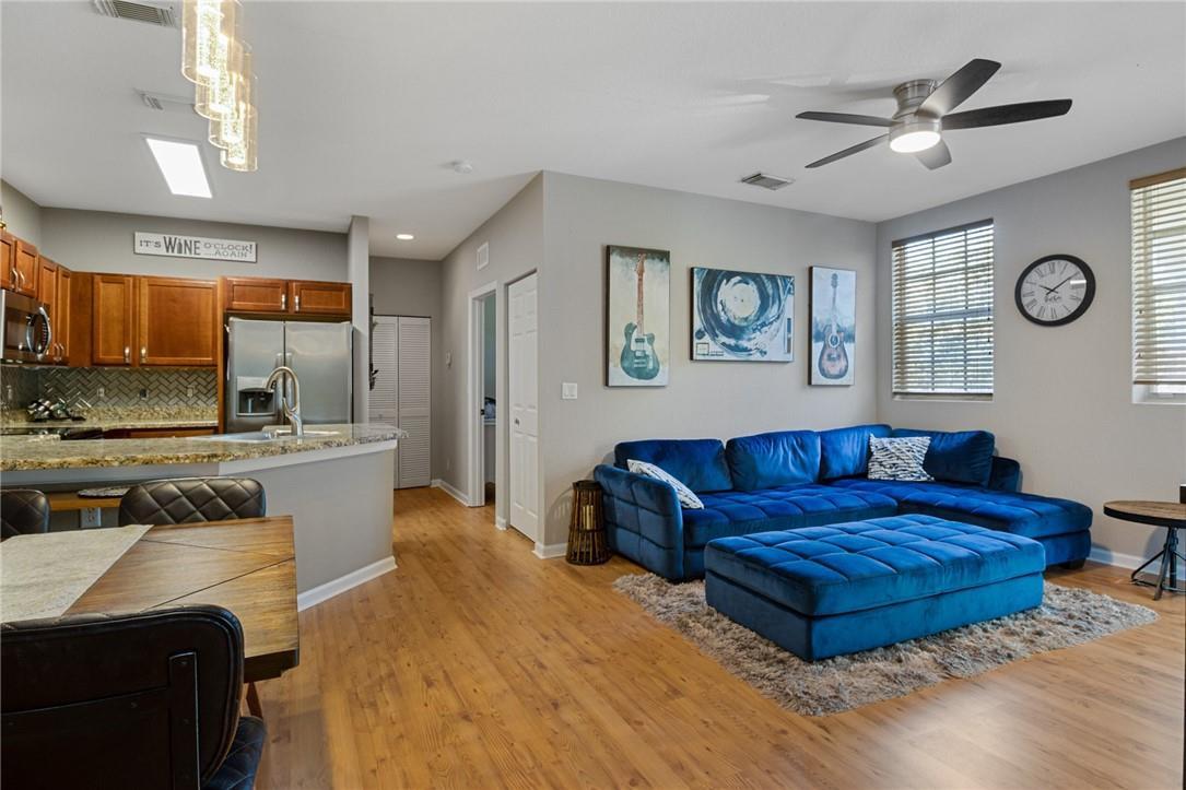 An open-concept living room and kitchen featuring a blue sectional sofa and wood flooring — 4809 N Wickham Circle # A, Delray Beach FL 33445, DELRAY BEACH, FL