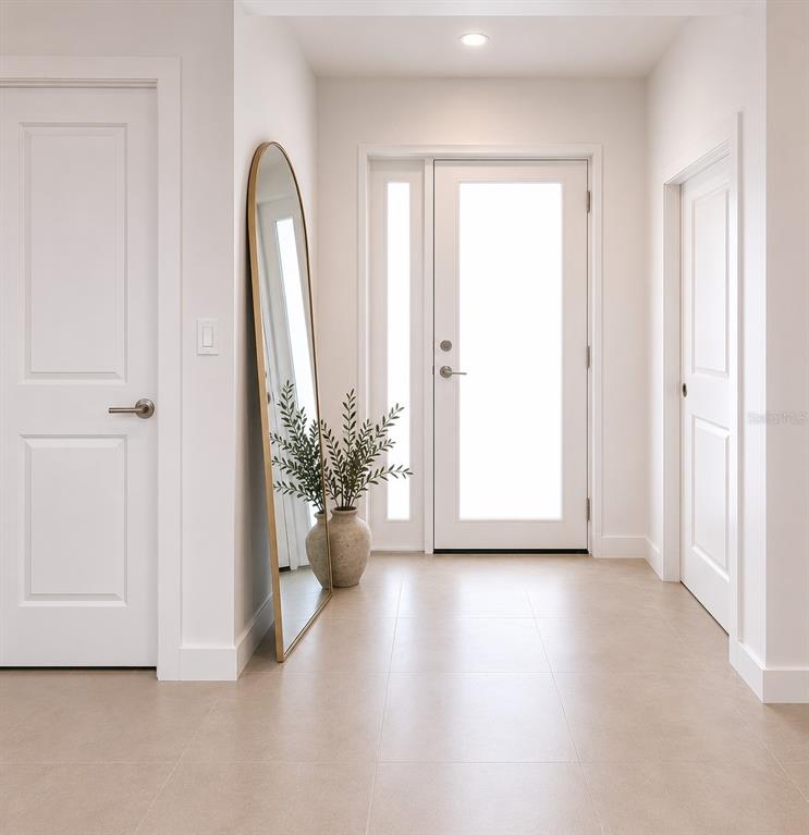 A bright entryway features light tile flooring, white doors, and a tall arched gold-framed mirror — 1401 W 10 ST. SELLER STRATA I STREET, LEHIGH ACRES, FL