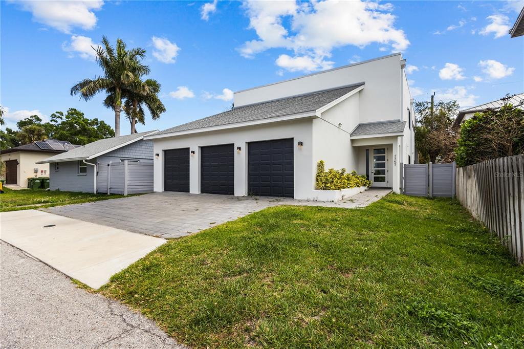 A modern white house with three dark garage doors and a paved driveway — 1755 7TH STREET, SARASOTA, FL