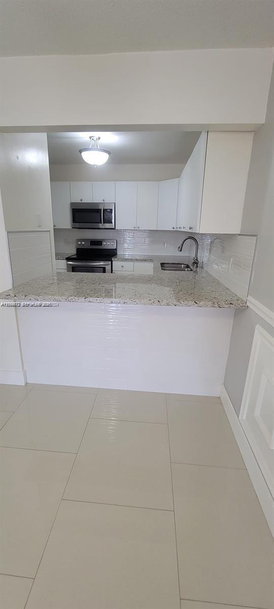 A kitchen features white cabinets, granite countertops, stainless steel appliances, and light-colored tile flooring — 6970 NW 186th St # 502, Hialeah FL 33015, HIALEAH, FL