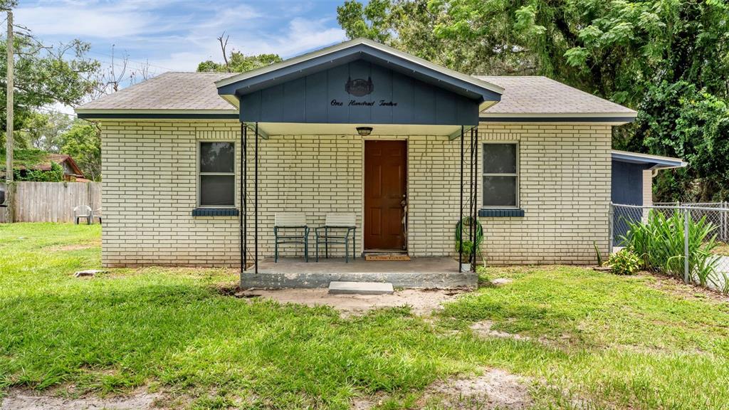 A single-story brick house features a covered front porch with two chairs and a door — 112 PALM DRIVE, WINTER HAVEN, FL