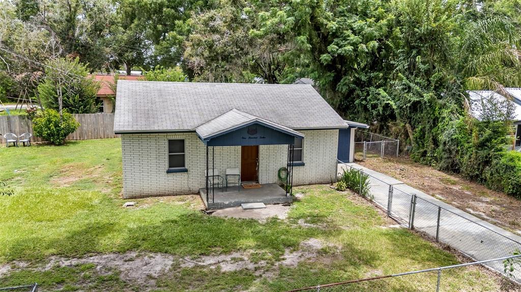 An exterior view of a single-story white brick house with a front porch and yard — 112 PALM DRIVE, WINTER HAVEN, FL