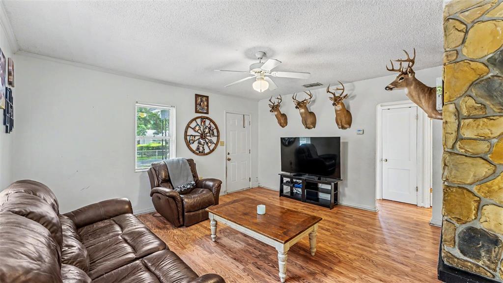 A living room features wood-look flooring, a leather sofa, a recliner, and mounted deer heads — 112 PALM DRIVE, WINTER HAVEN, FL