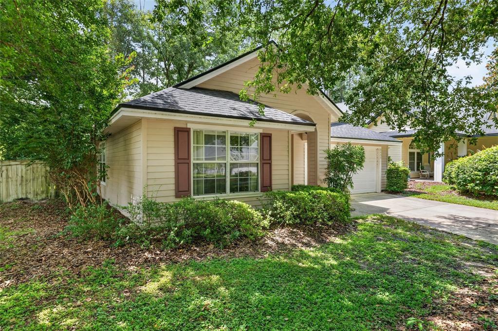 A tan, single-story house with a gabled roof, dark shutters, and a concrete driveway — 9437 SW 31ST LANE, GAINESVILLE, FL
