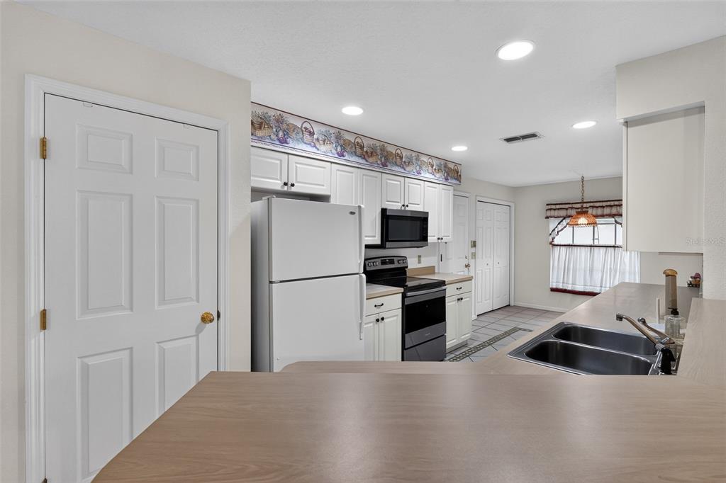 A kitchen features white cabinets, a white refrigerator, a black stove, and a wood-look countertop — 110 MORNING GLORY CIRCLE, WINTER HAVEN, FL