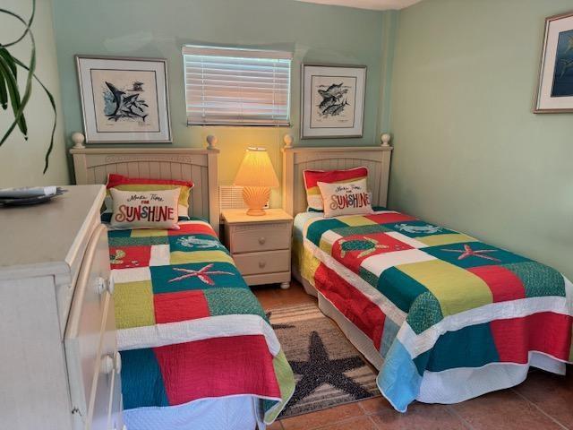 A bedroom features two twin beds with colorful patchwork quilts and a central nightstand — 309 W Calzada De Bougainvillea, Marathon FL 33050, MARATHON, FL
