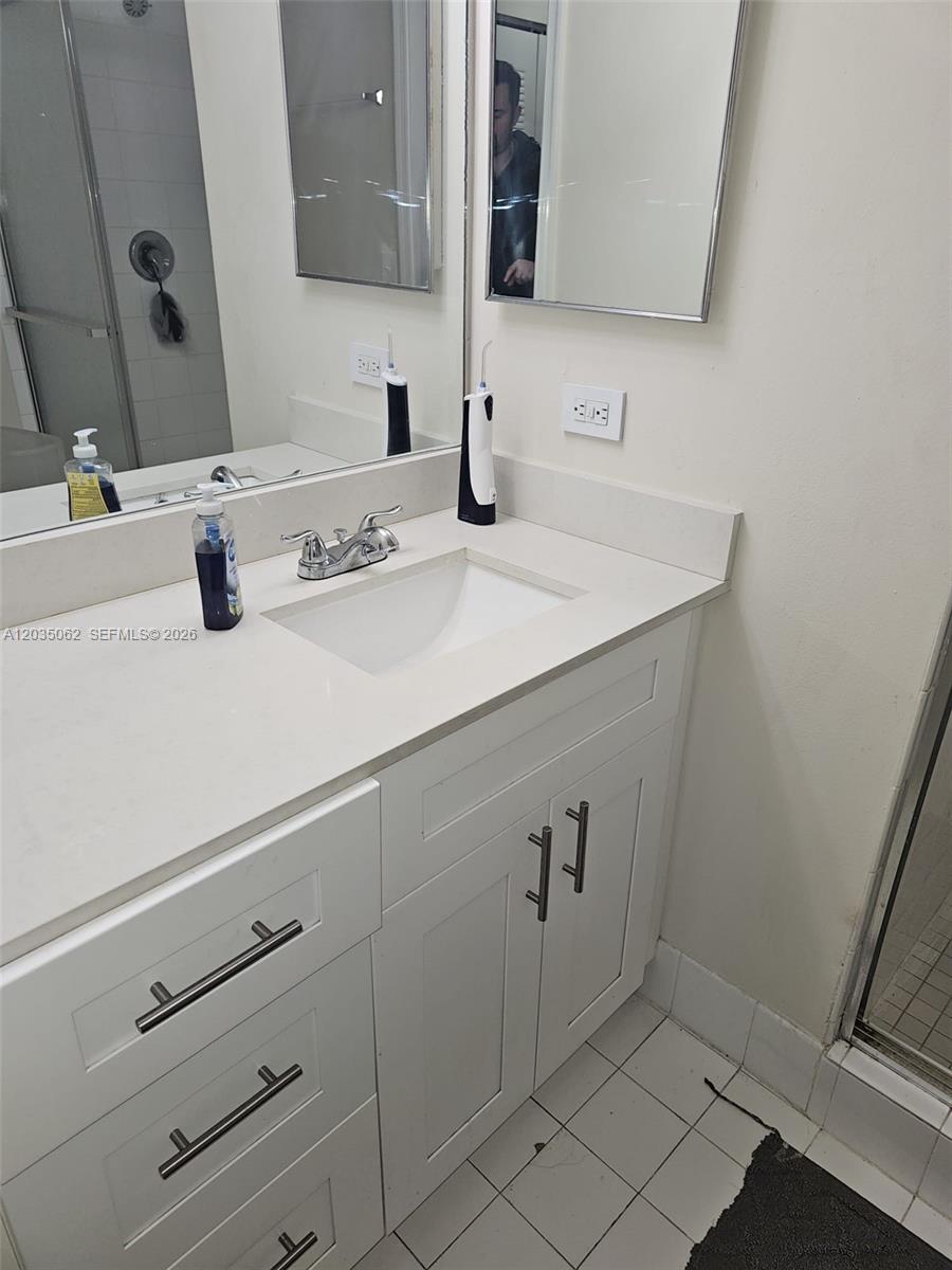A bathroom features a white vanity with a quartz countertop, dual mirrors, and a shower — 2031 RENAISSANCE BLVD # 205, Miramar FL 33025, MIRAMAR, FL