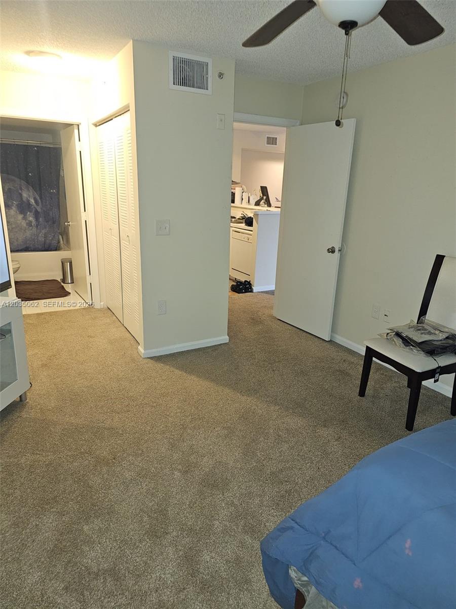 A carpeted bedroom features a bathroom entrance, a closet, and a doorway leading to a kitchen — 2031 RENAISSANCE BLVD # 205, Miramar FL 33025, MIRAMAR, FL