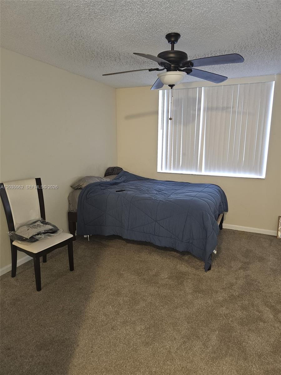 A bedroom features a bed with a blue comforter, a ceiling fan, and a chair — 2031 RENAISSANCE BLVD # 205, Miramar FL 33025, MIRAMAR, FL