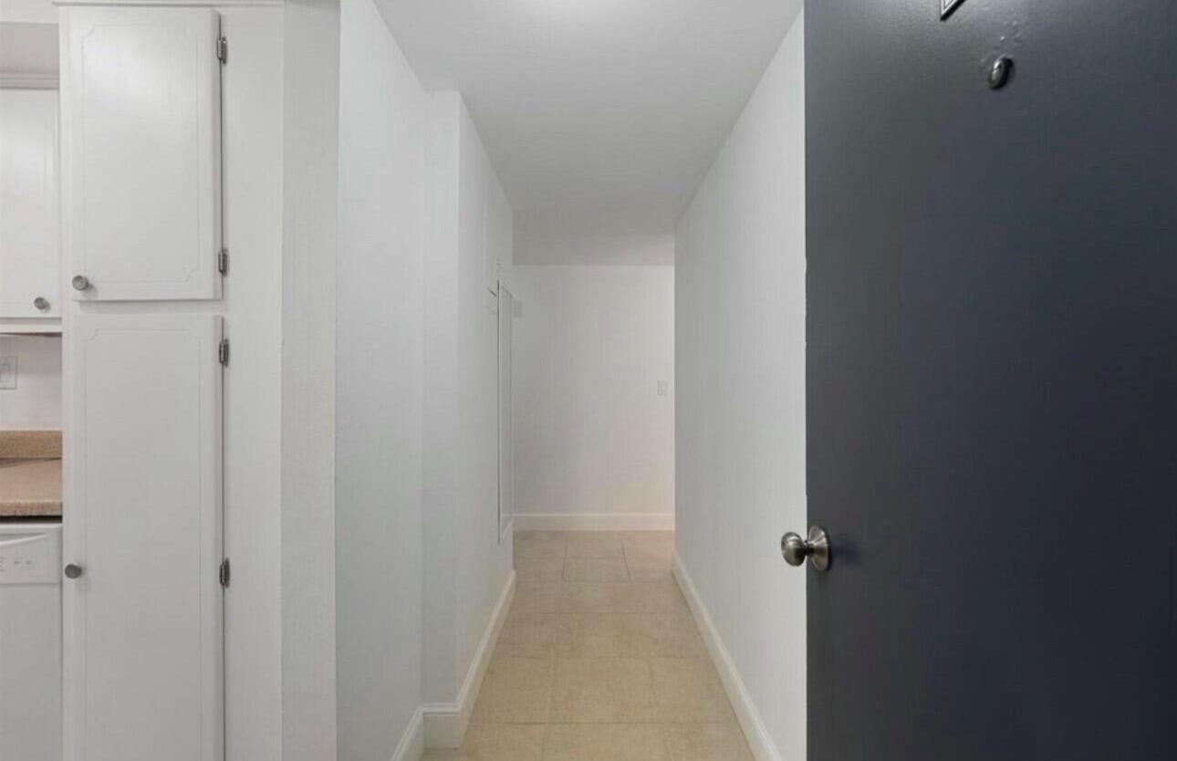 A hallway with white walls and tile flooring leads toward an open interior space — 1601 S Flagler Drive # 106o, West Palm Beach FL 33401, WEST PALM BEACH, FL