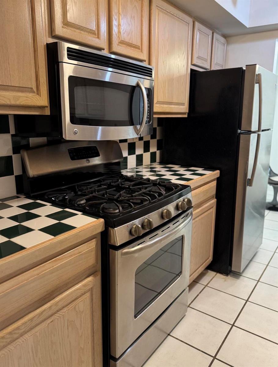 A kitchen features oak cabinets, stainless steel appliances, and a green and white checkered countertop — 1601 S Flagler Drive # 106o, West Palm Beach FL 33401, WEST PALM BEACH, FL