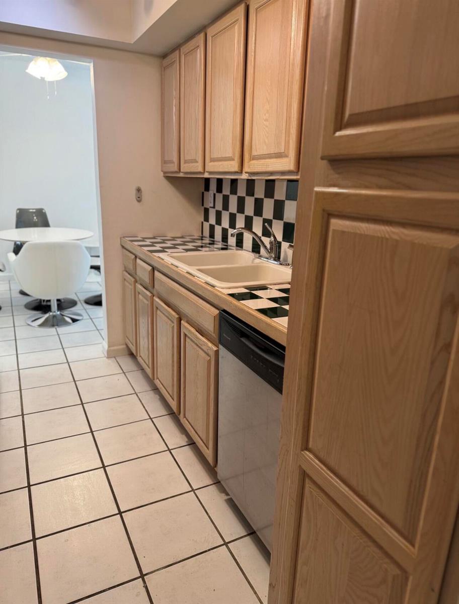 A kitchen features light wood cabinets, a black and white checkered backsplash, and tile flooring — 1601 S Flagler Drive # 106o, West Palm Beach FL 33401, WEST PALM BEACH, FL