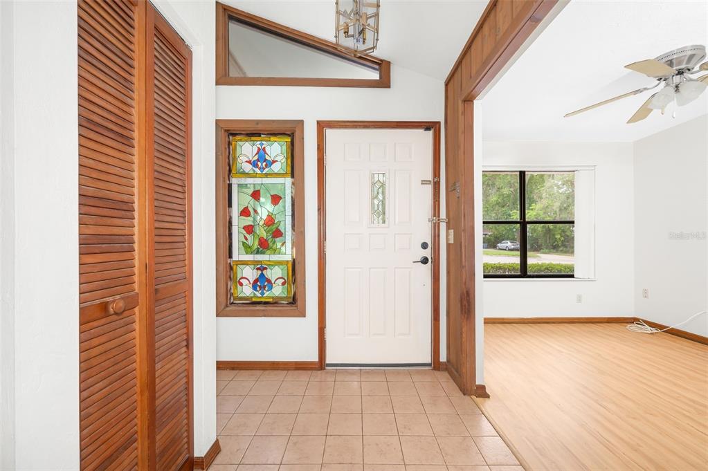 An entryway with tiled floors, a stained-glass window, a white door, and wood-paneled trim — 1301 NW 94TH STREET, GAINESVILLE, FL