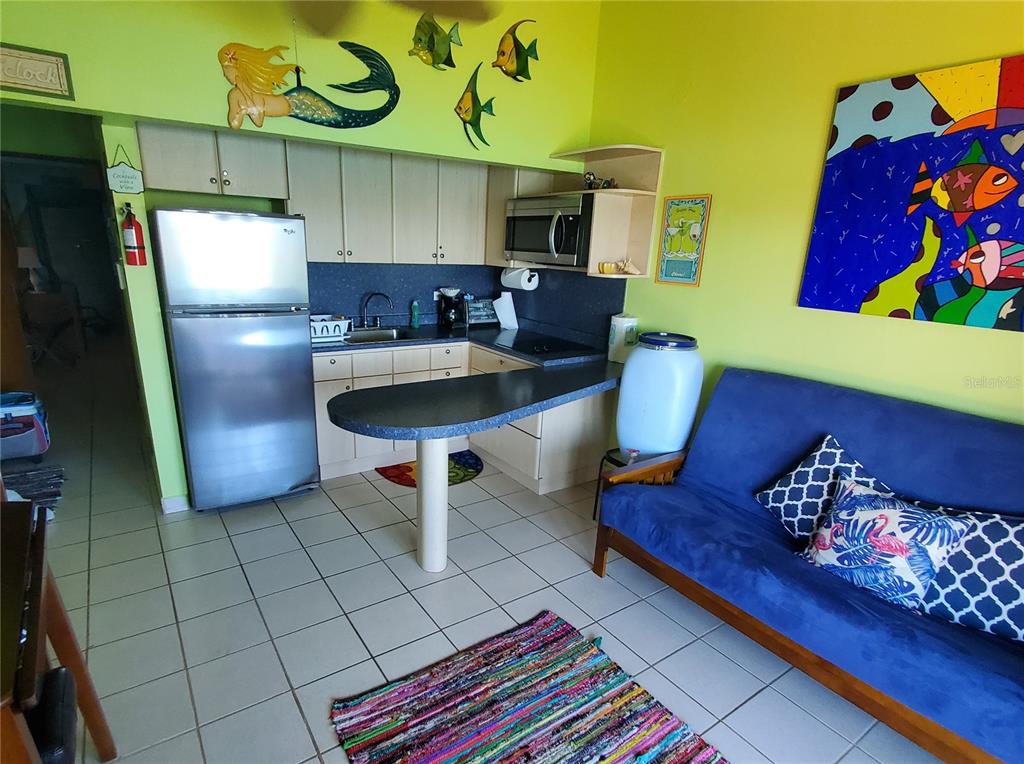 A kitchen with light cabinets and a blue breakfast bar sits next to a blue sofa — D201 BAHIA MARINA RESORT CONDOMINIUM UNIT D201, CULEBRA, PR