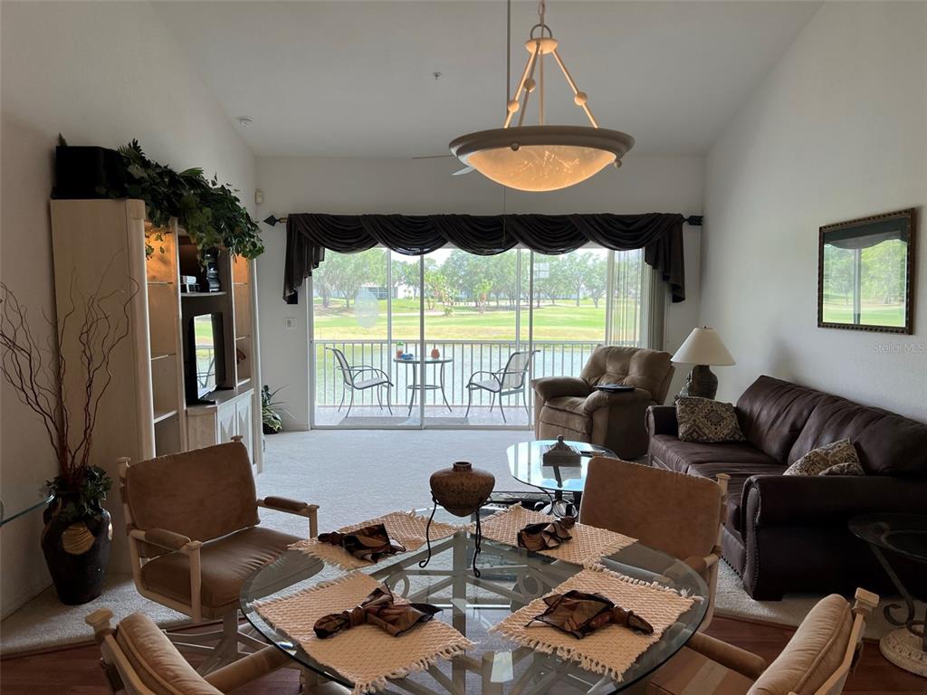A living and dining area features a glass table, brown sofa, and sliding glass doors — 6632 PINEVIEW TERRACE UNIT 10-201, BRADENTON, FL