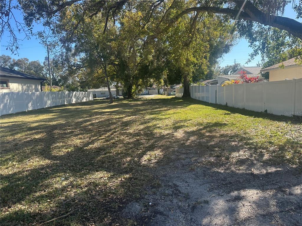 A grassy, rectangular vacant lot is enclosed by white vinyl privacy fences on both sides — 2710 W LAKE AVENUE, TAMPA, FL