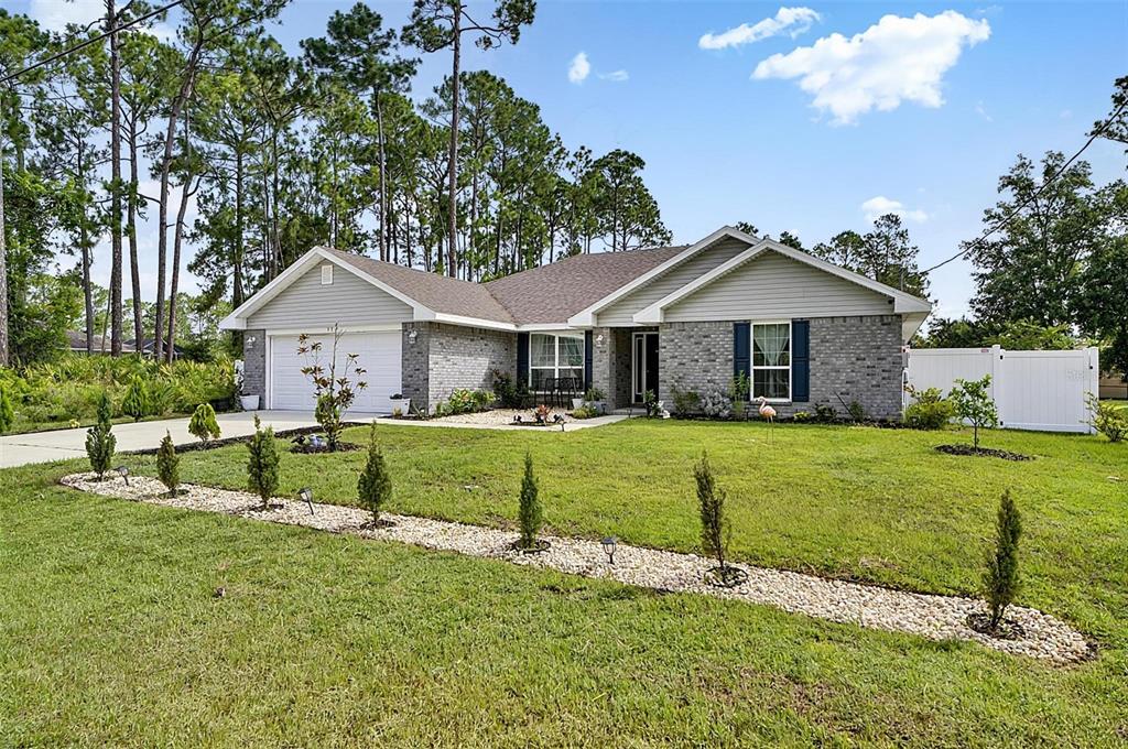 A single-story house with a gray brick and siding exterior, a garage, and landscaped lawn — 33 RICHARDSON DRIVE, PALM COAST, FL