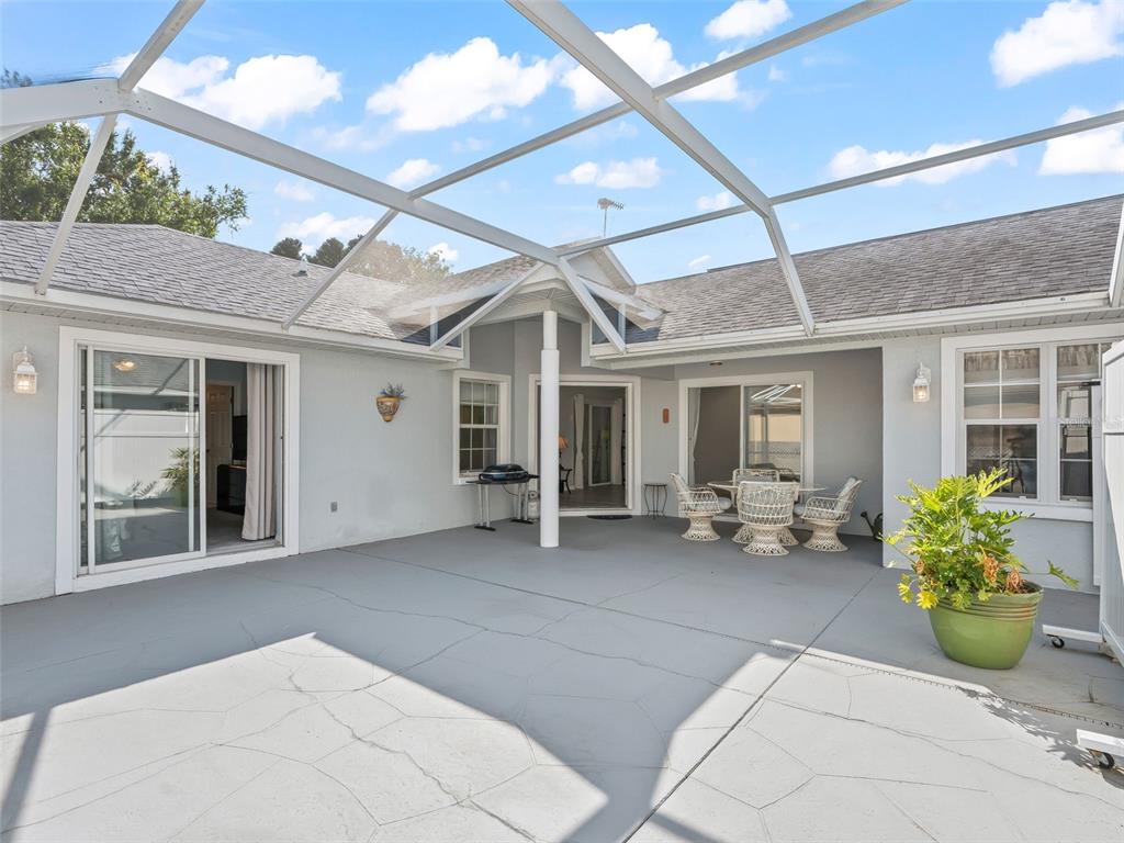 A covered concrete patio features a screened enclosure, outdoor furniture, and sliding glass doors — 17789 SE 113TH TERRACE, SUMMERFIELD, FL