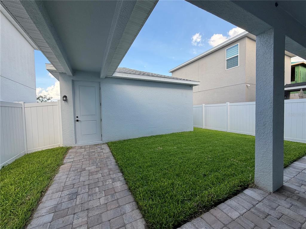 A paved walkway leads to a white door on the side of a stucco house — 12899 WESTHAVEN OAK DRIVE, WINTER GARDEN, FL