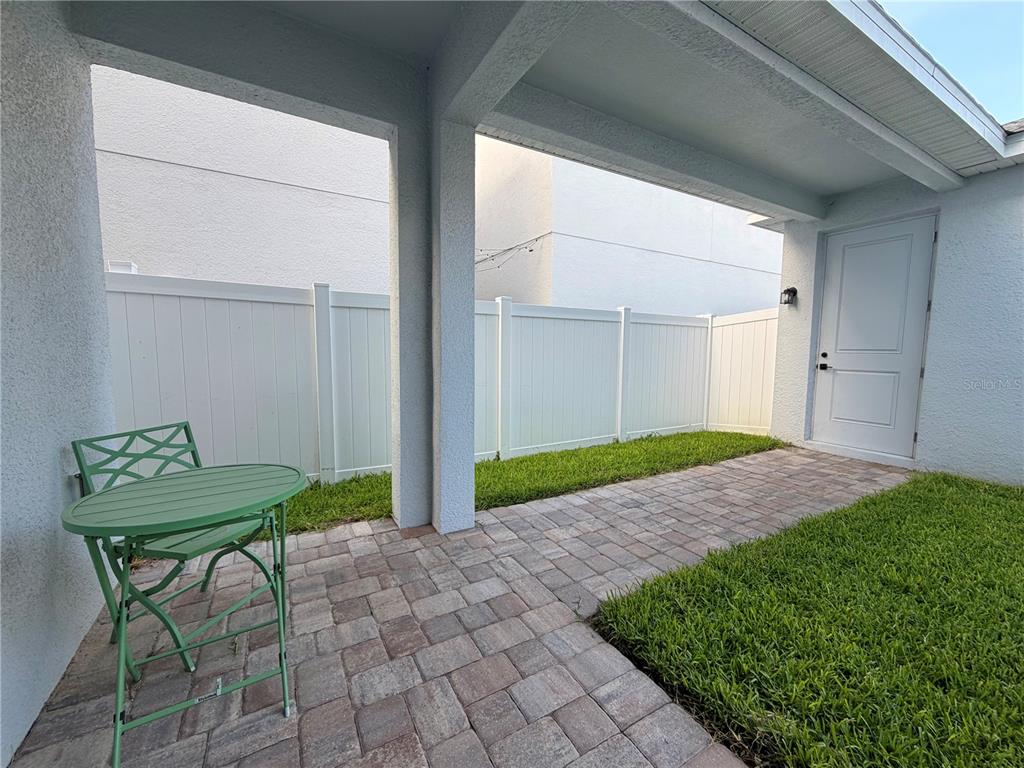 A paved patio with a green bistro set sits under a covered entryway — 12899 WESTHAVEN OAK DRIVE, WINTER GARDEN, FL