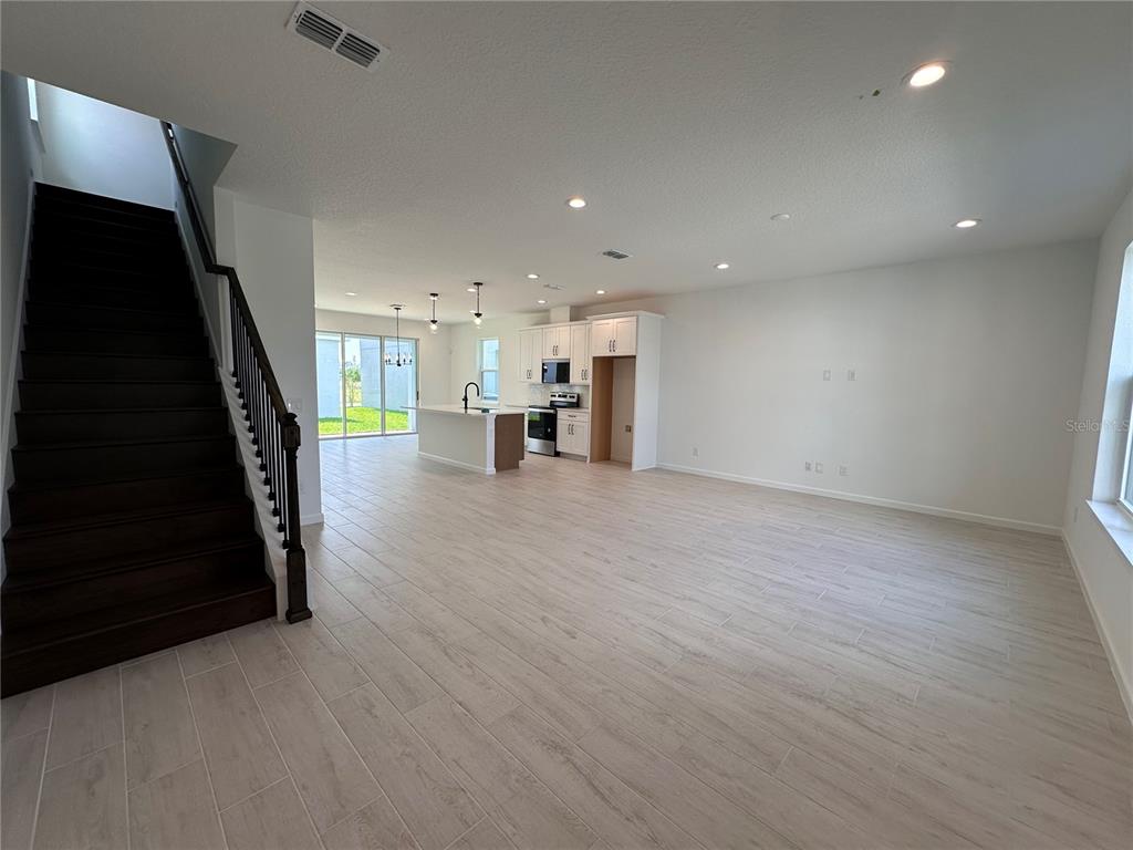 An open-concept living area features a kitchen with white cabinets and wood-look tile flooring — 12899 WESTHAVEN OAK DRIVE, WINTER GARDEN, FL