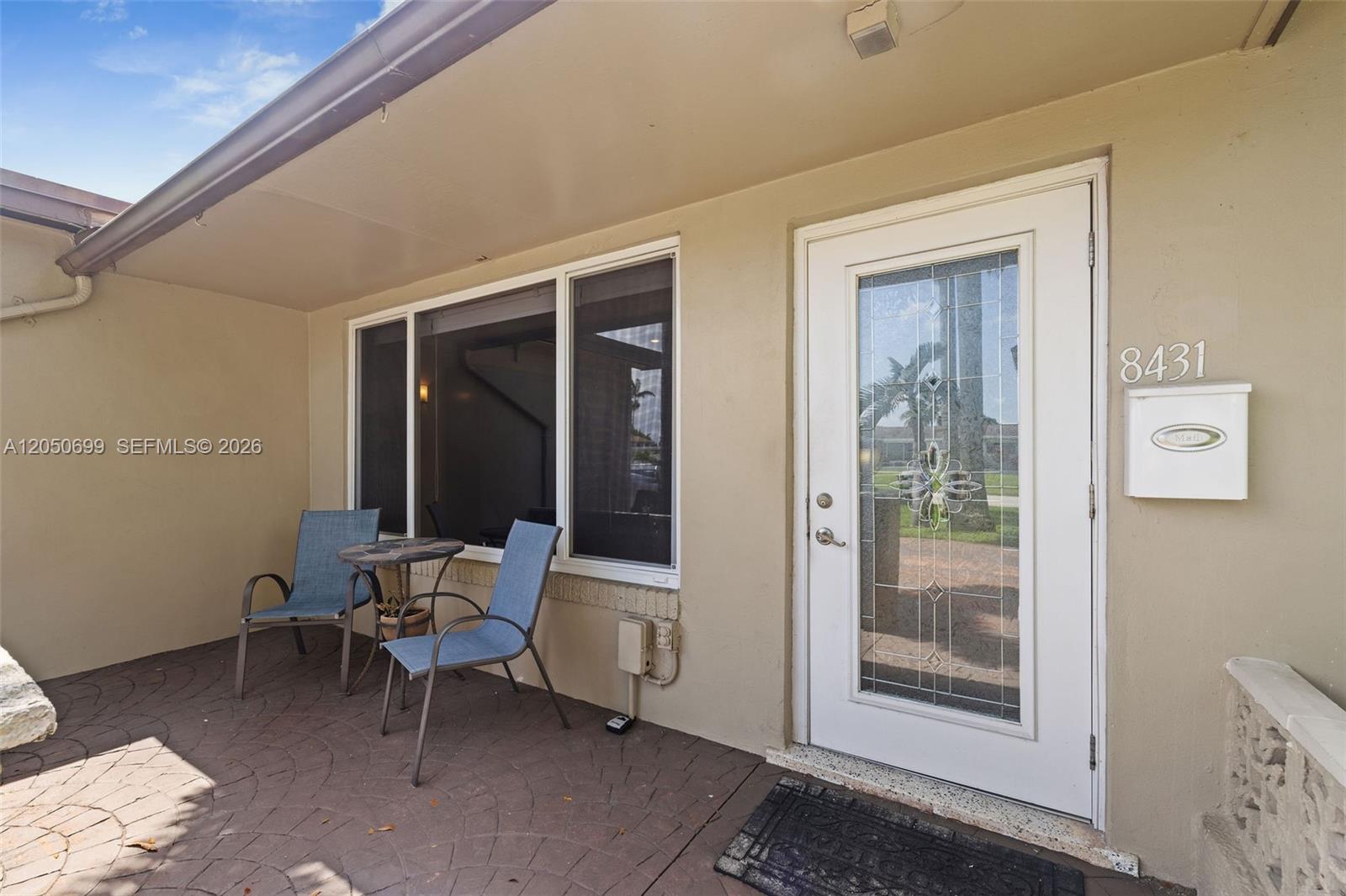 A patio with two chairs and a small table sits outside a white front door — 8431 Pasadena Blvd, Pembroke Pines FL 33024, PEMBROKE PINES, FL