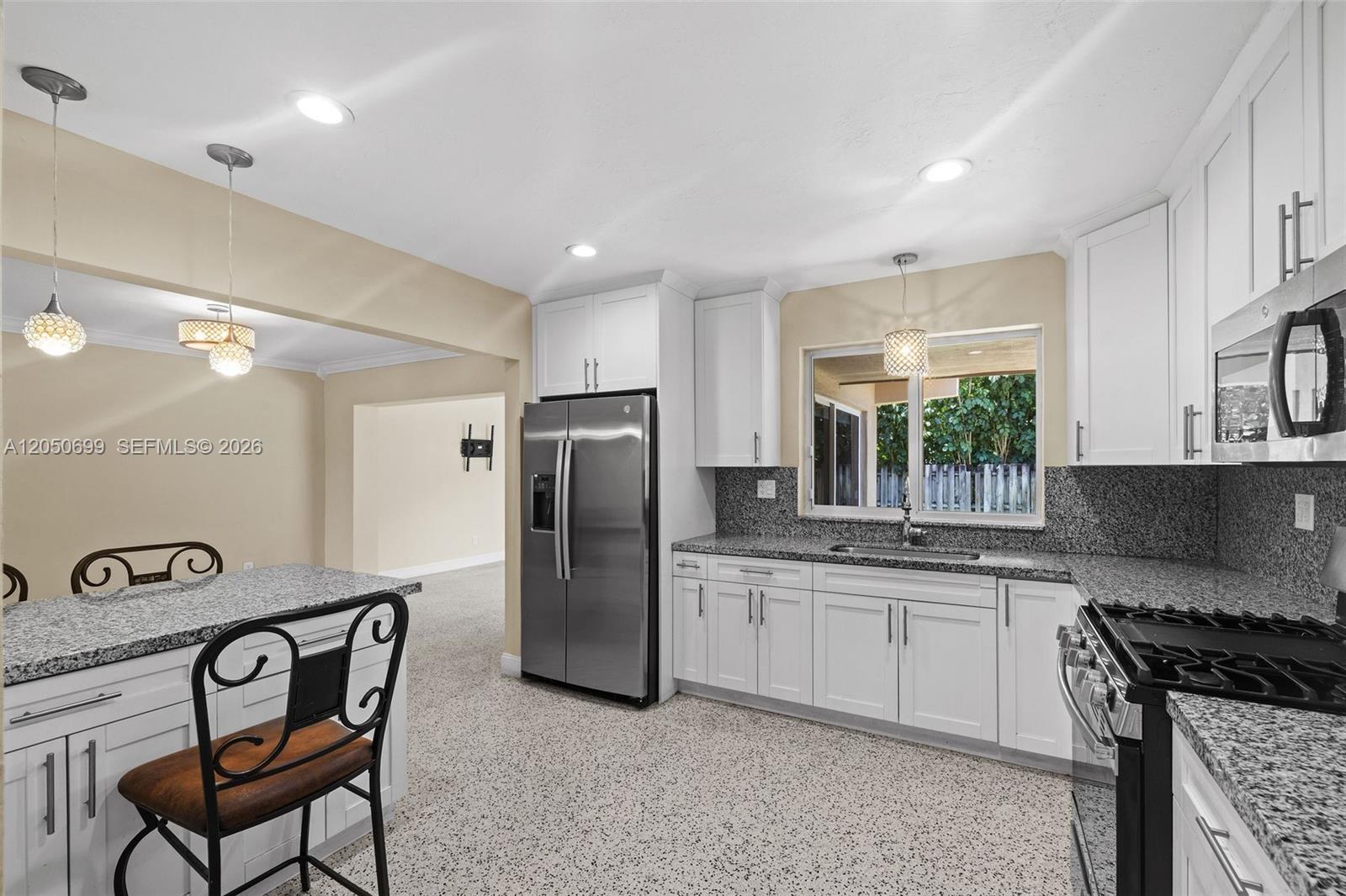 A kitchen features white cabinets, granite countertops, stainless steel appliances, and a speckled floor — 8431 Pasadena Blvd, Pembroke Pines FL 33024, PEMBROKE PINES, FL