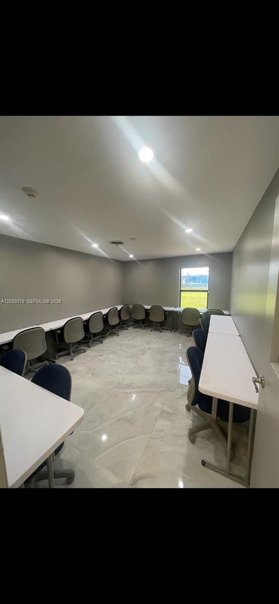 A classroom-style room features white tables, rolling chairs, gray walls, and light-colored tile flooring — 5851 NW 17th Ave, Miami FL 33142, MIAMI, FL
