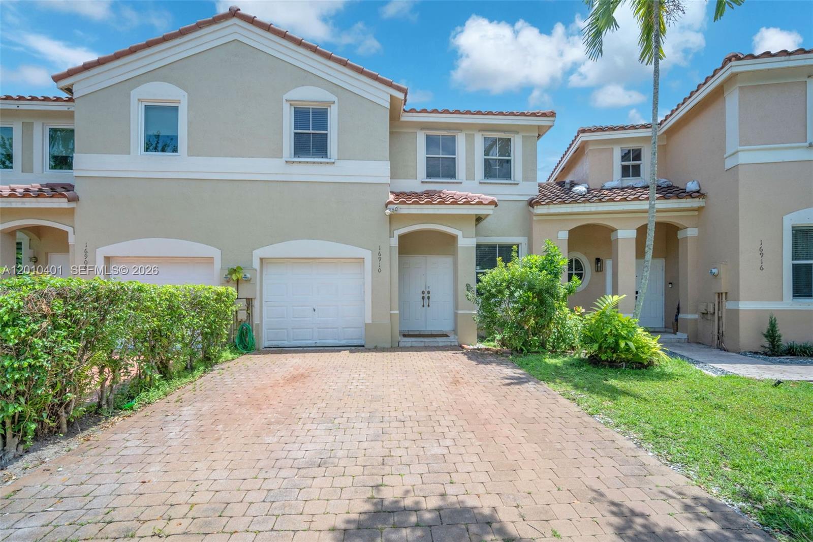 A two-story tan stucco townhouse with a brick paver driveway and a single-car garage — 16910 SW 39th Ct, Miramar FL 33027, MIRAMAR, FL