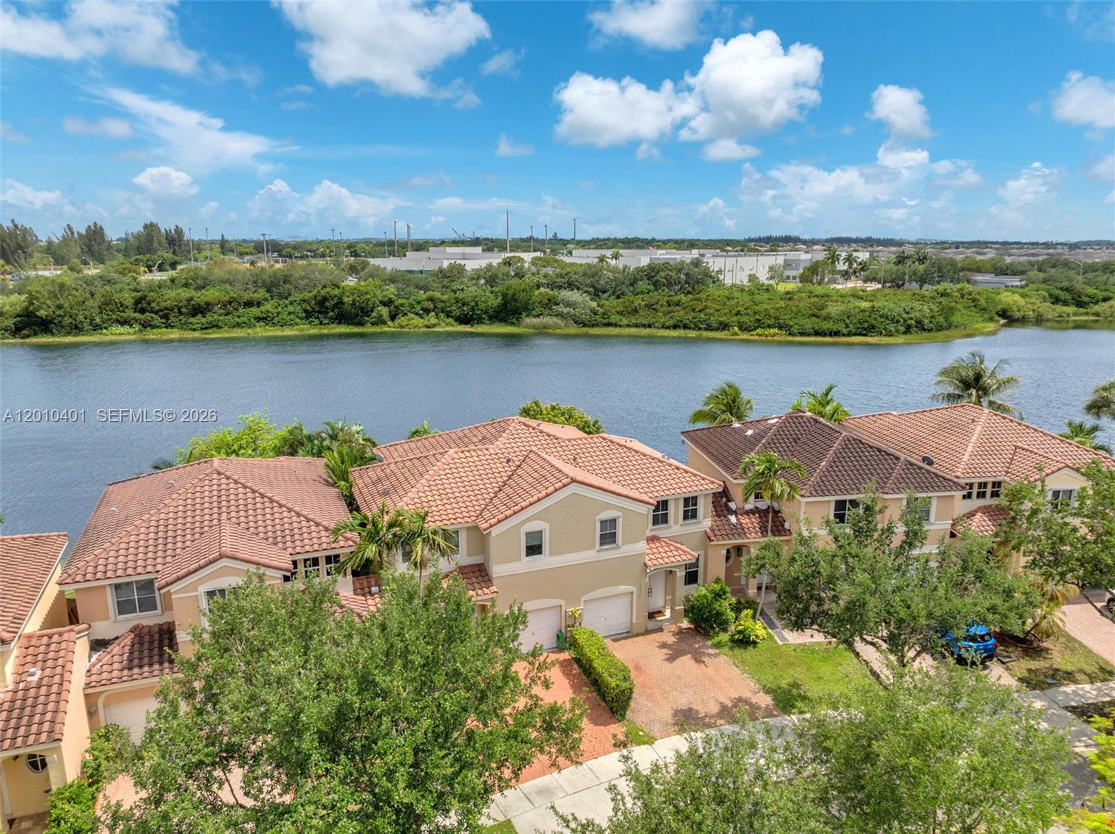 An aerial view shows suburban townhomes with terracotta roofs situated along a lake — 16910 SW 39th Ct, Miramar FL 33027, MIRAMAR, FL