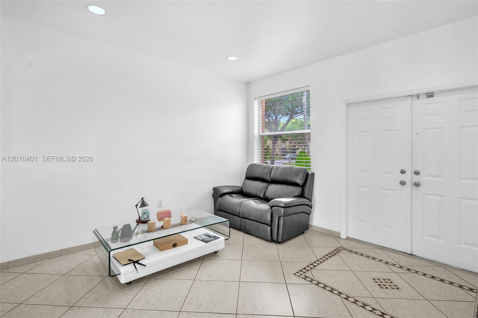 A living room features white walls, tile flooring, a glass coffee table, and a loveseat — 16910 SW 39th Ct, Miramar FL 33027, MIRAMAR, FL