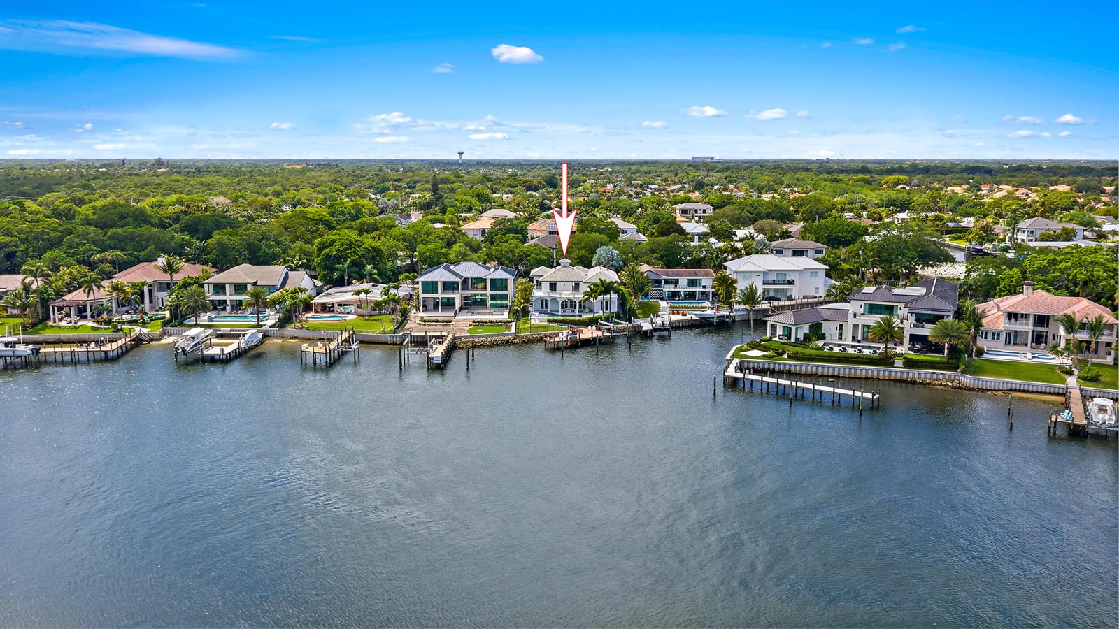 A covered patio with white wicker furniture overlooks a swimming pool and a waterfront canal — 12864 S Shore Drive, Palm Beach Gardens FL 33410, PALM BEACH GARDENS, FL