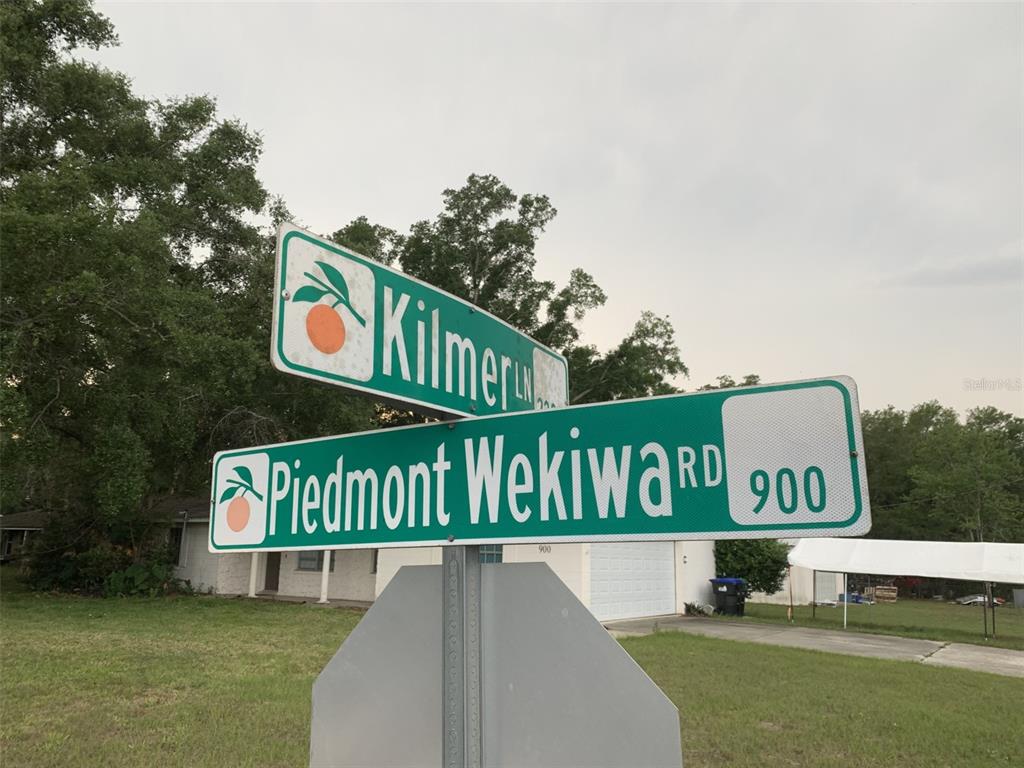 A street sign displays the intersection of Kilmer Lane and Piedmont Wekiwa Road — 2223 KILMER LANE, APOPKA, FL