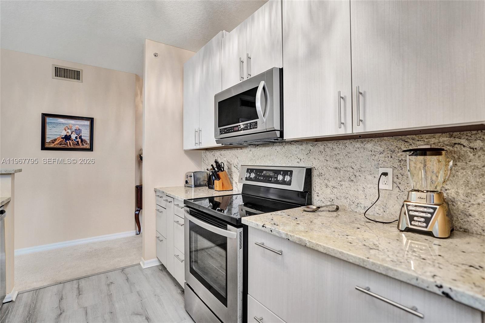 A kitchen features light wood cabinets, granite countertops, and stainless steel appliances — 2421 NE 65th St # 202, Fort Lauderdale FL 33308, FORT LAUDERDALE, FL