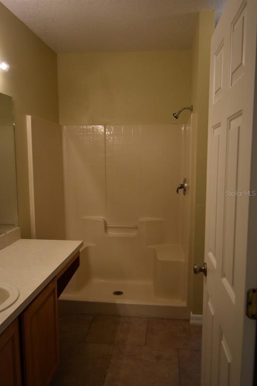 A bathroom featuring a vanity with a sink and a white fiberglass shower stall — 929 GLOUCESTER COURT, KISSIMMEE, FL