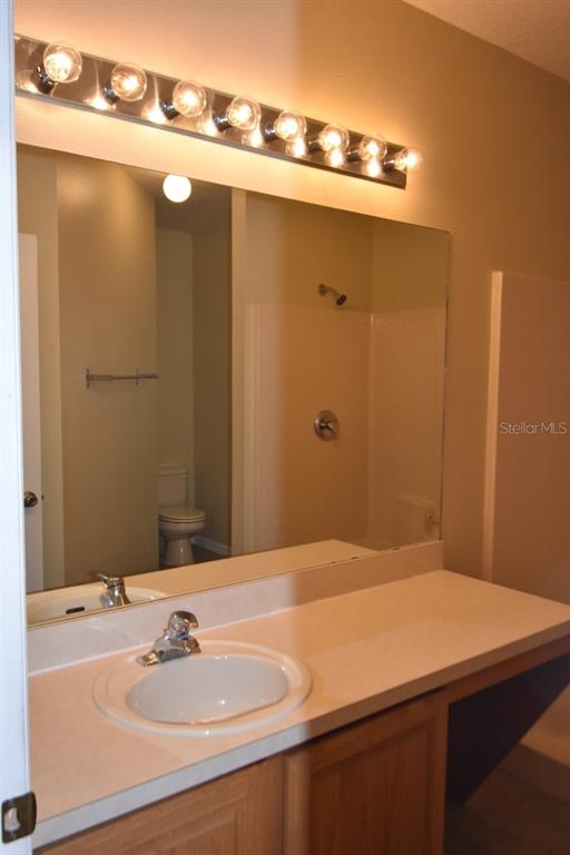A bathroom features a vanity with a white countertop, a mirror, and a light fixture — 929 GLOUCESTER COURT, KISSIMMEE, FL