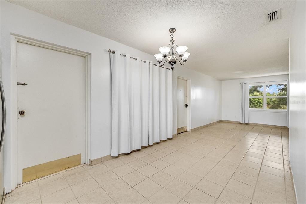 A room with beige tile flooring, white walls, a chandelier, and a white curtain partition — 4304 LONDON TOWN ROAD UNIT D224, TITUSVILLE, FL