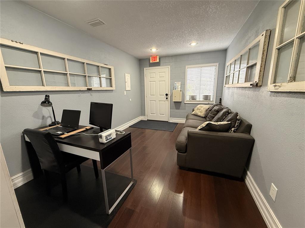 A home office features a desk, a gray sofa, and decorative window frames on blue walls — 245 W BLUE SPRINGS AVENUE UNIT E, ORANGE CITY, FL