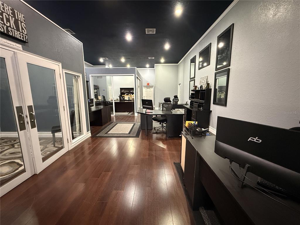 An office space features dark wood flooring, black ceilings, and multiple desks with computer monitors — 245 W BLUE SPRINGS AVENUE UNIT E, ORANGE CITY, FL