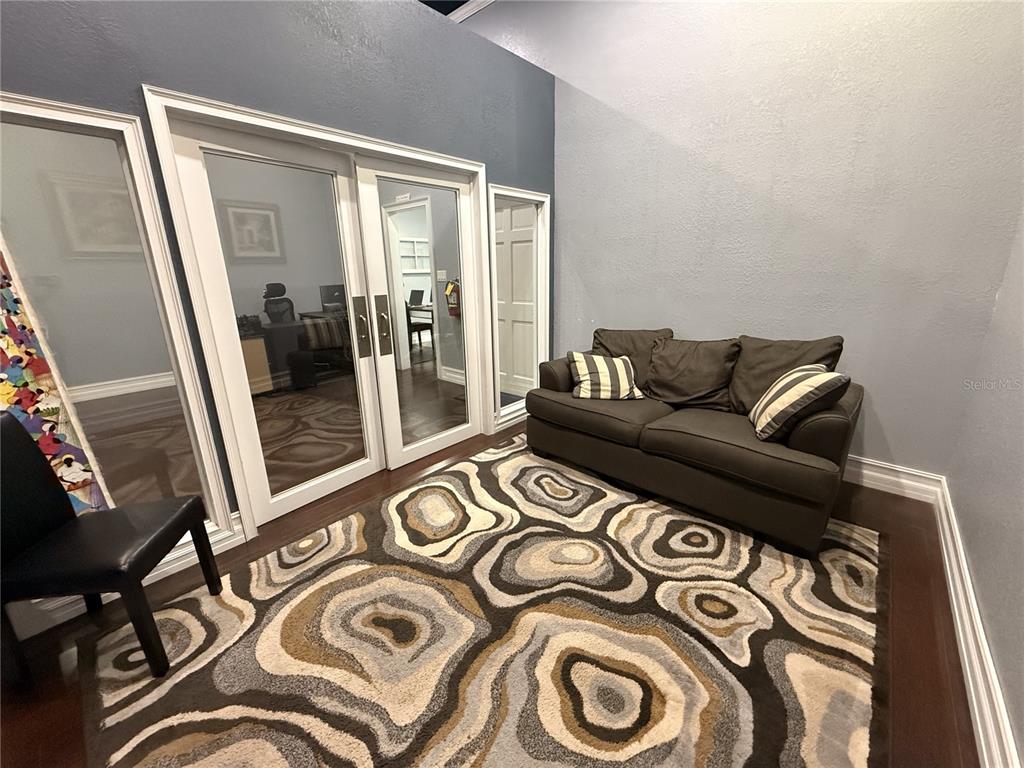 A room with dark wood floors, a patterned area rug, a sofa, and glass-paned doors — 245 W BLUE SPRINGS AVENUE UNIT E, ORANGE CITY, FL