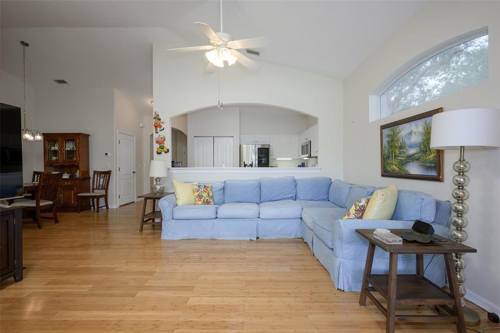 A living room features a blue sectional sofa, light wood flooring, and an arched wall opening — 21 SUMMERWIND CIRCLE UNIT 107, PALM COAST, FL