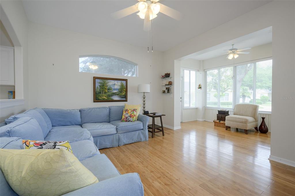 A living room features a blue sectional sofa, hardwood floors, and large windows — 21 SUMMERWIND CIRCLE UNIT 107, PALM COAST, FL