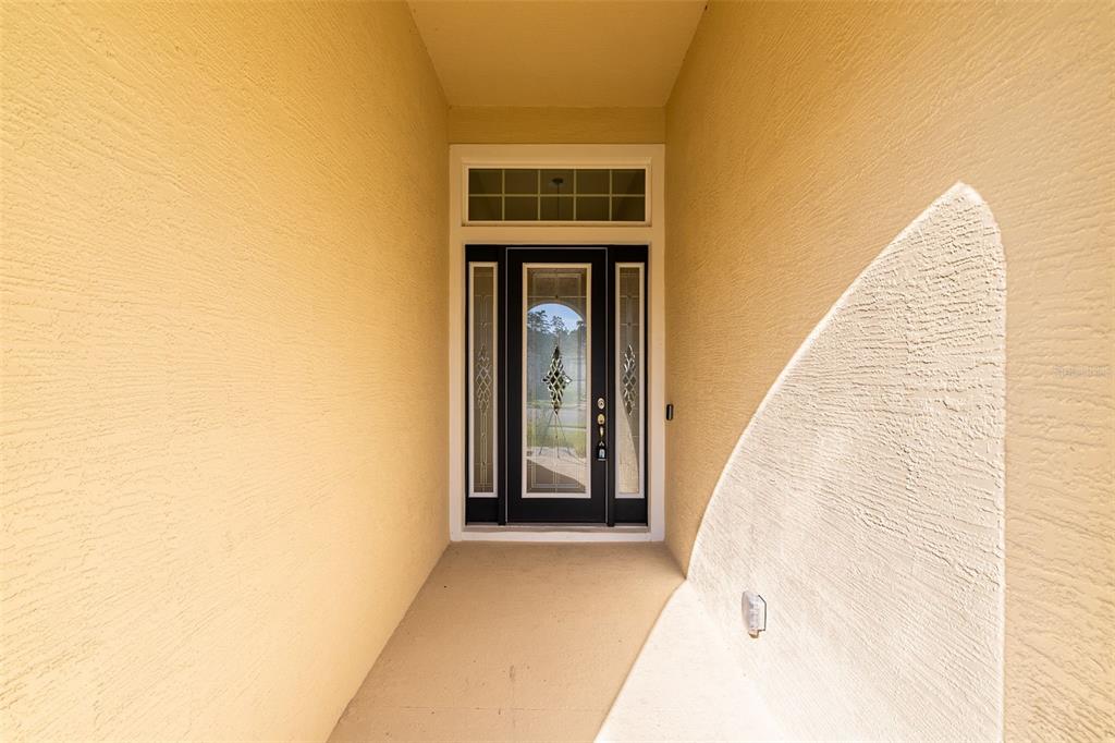 A covered entryway features a front door with glass panels and a transom window — 525 MOSAIC BOULEVARD, DAYTONA BEACH, FL