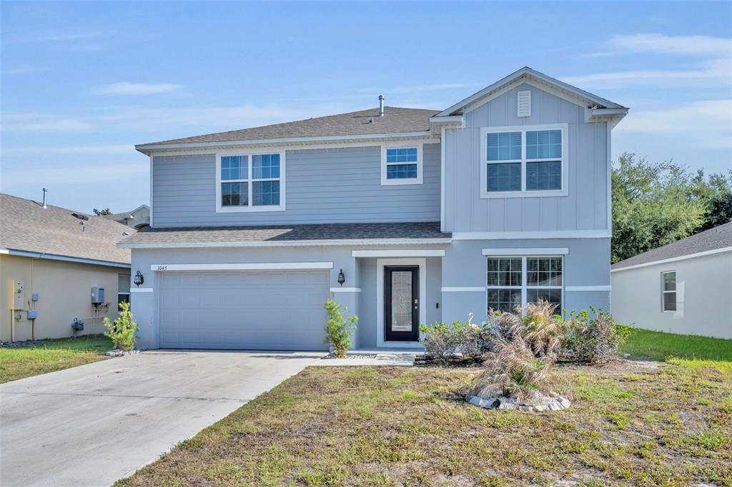 A two-story, light blue house with a two-car garage and a concrete driveway — 1045 BRADFORD RIDGE DRIVE, LEESBURG, FL